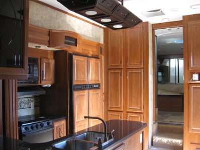 Wood-paneled walls and shelves of an RV that act as a storage vessel.