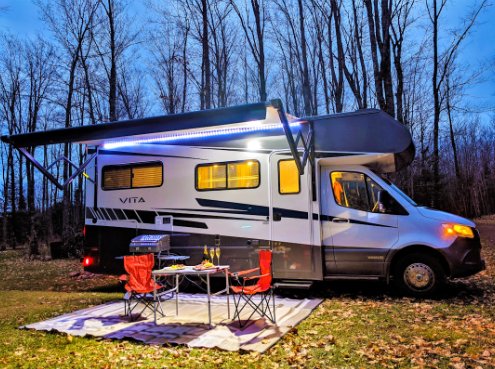 RV at night with it's awning down in the forest around Walcott, IA.