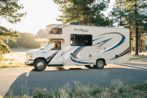 Couple driving their RV along a scenic route surrounded by vibrant early fall foliage.