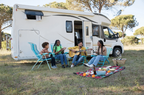 Friends sitting outside their RV playing the guitar.