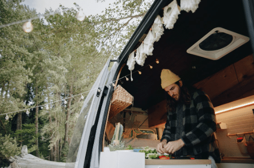 Man cooking out of his RV in snowy weather.