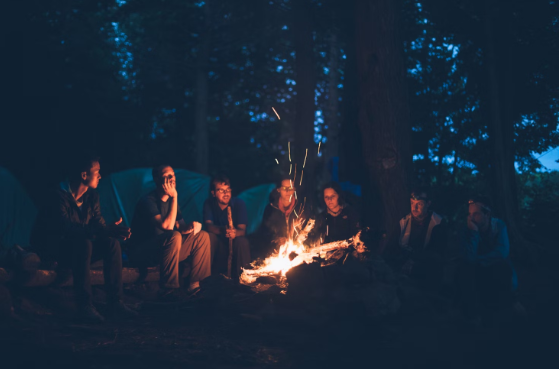 Friends hanging out around a night time campfire at a Quad Cities area campground.