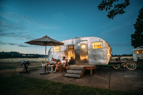 A couple sitting in front of their travel trailer at night in a RV campground.