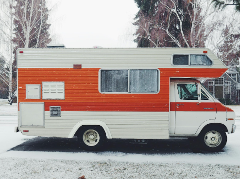 RV with orange paint accents parked on a snowy road.