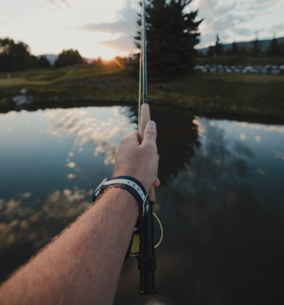 Man holding a fishing rod casting into an Iowa pond.