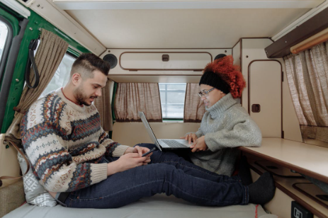 A couple using their laptops inside their travel trailer using wifi.