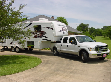 White pickup truck hauling a fifth wheel travel trailer.