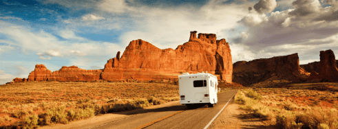 RV traveling through desert environment on a long stretch of highway.